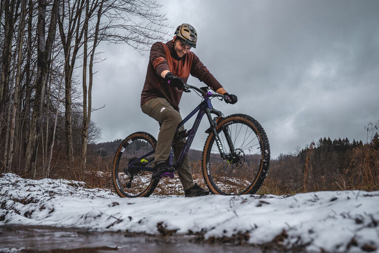 Adam Sauerwein smiling on a bike in a snowy forest area.